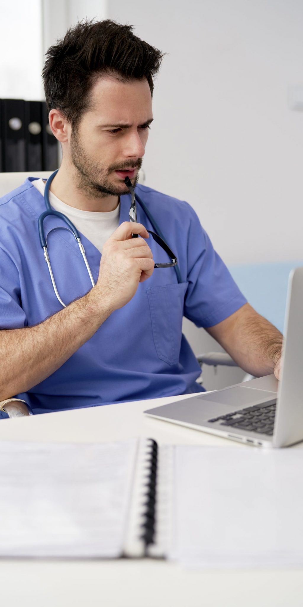 Focused doctor using laptop in doctor’s office Focused doctor using laptop in doctor's office